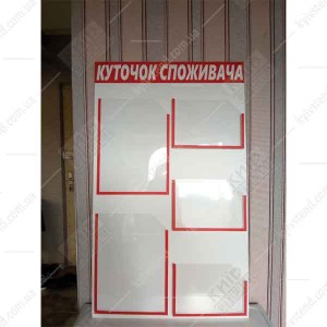 Інформаційний стенд куточок споживача білого і червоного кольору з прозорими кишенями встановлений біля входу у торгову точку -фото ліворуч