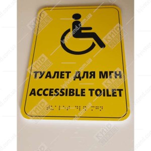 Тактильна табличка туалет для МГН зі шрифтом Брайля на білому ПВХ пластику, встановлена біля входу в санвузол- фото праворуч.