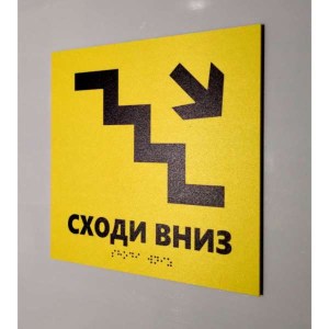 Тактильна табличка жовтого кольору зі шрифтом Брайля та піктограмою сходів вниз - фотографія ліворуч.