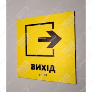 Тактильна табличка вихід зі стрілкою вправо на жовтому пластиковому фоні зі шрифтом Брайля фото на стіні праворуч