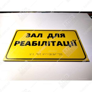 Тактильна табличка з написом Зал для реабілітації - фотографія знизу на стіні.
